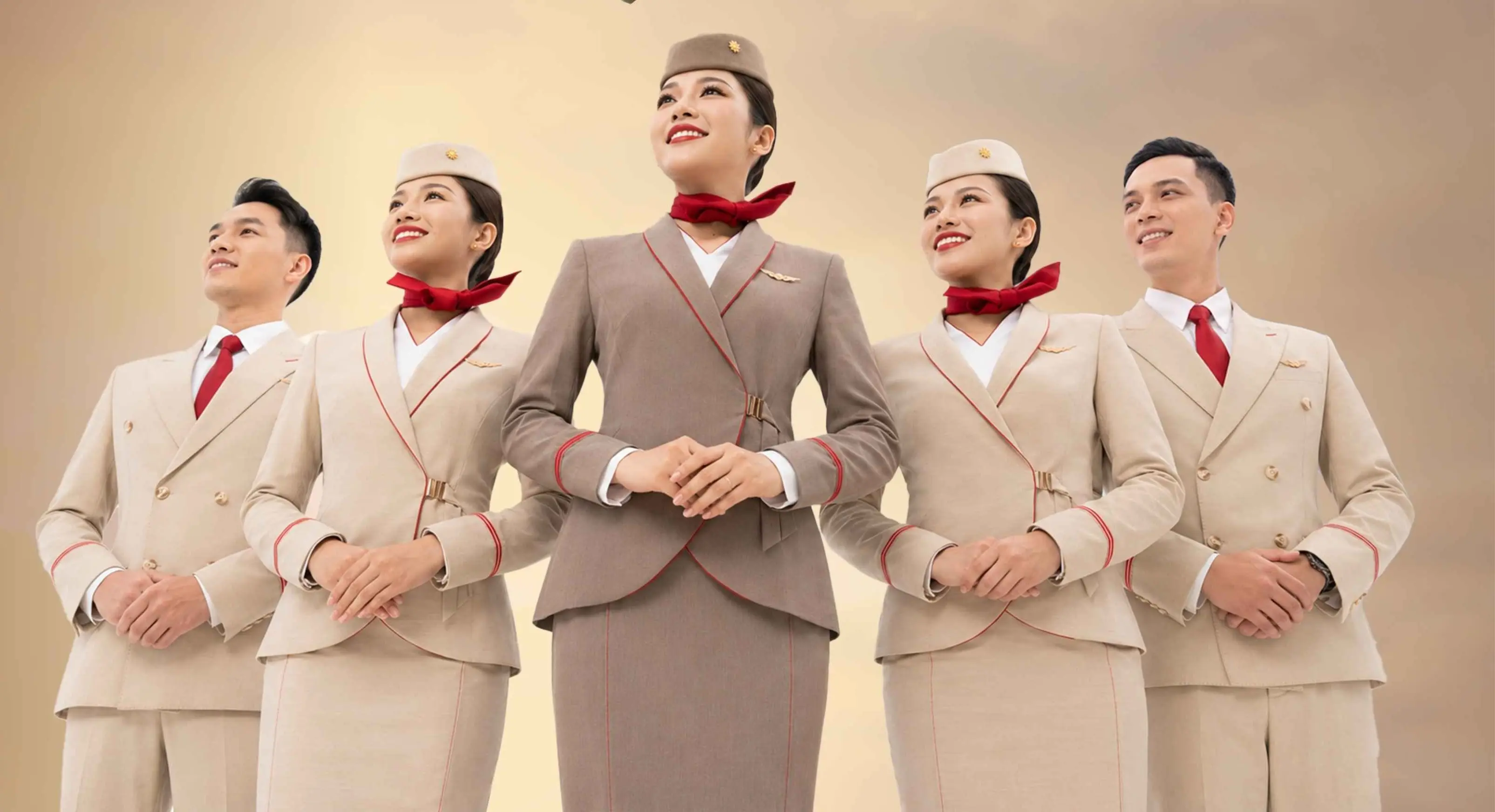 ลูกเรือ Sun PhuQuoc Airways ห้าคนในชุดยูนิฟอร์มสีครีมและน้ำตาล ยืนเรียงกันยิ้ม